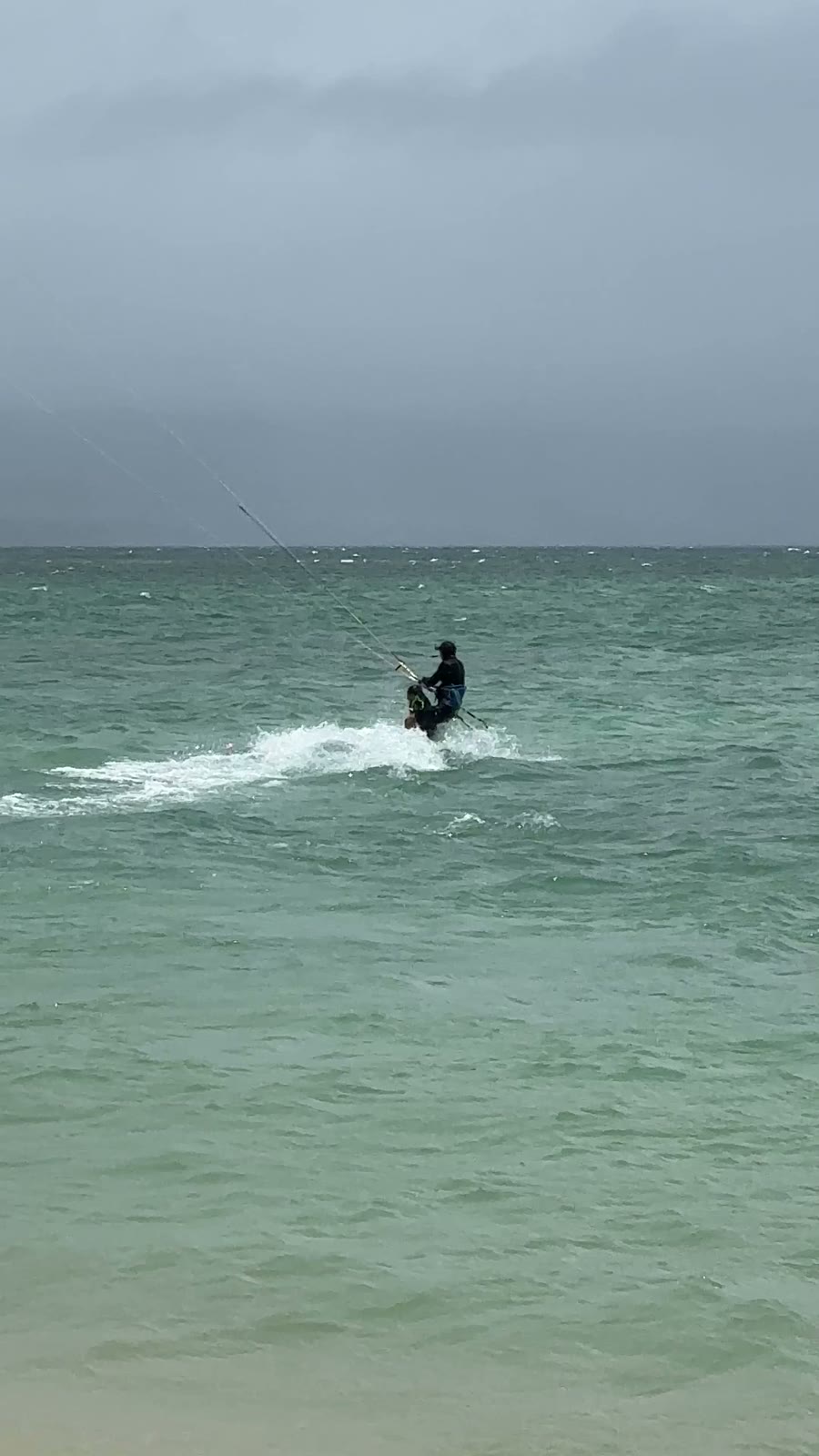 Andrey riding the kiteboard with Aiden standing in front of him, holding on