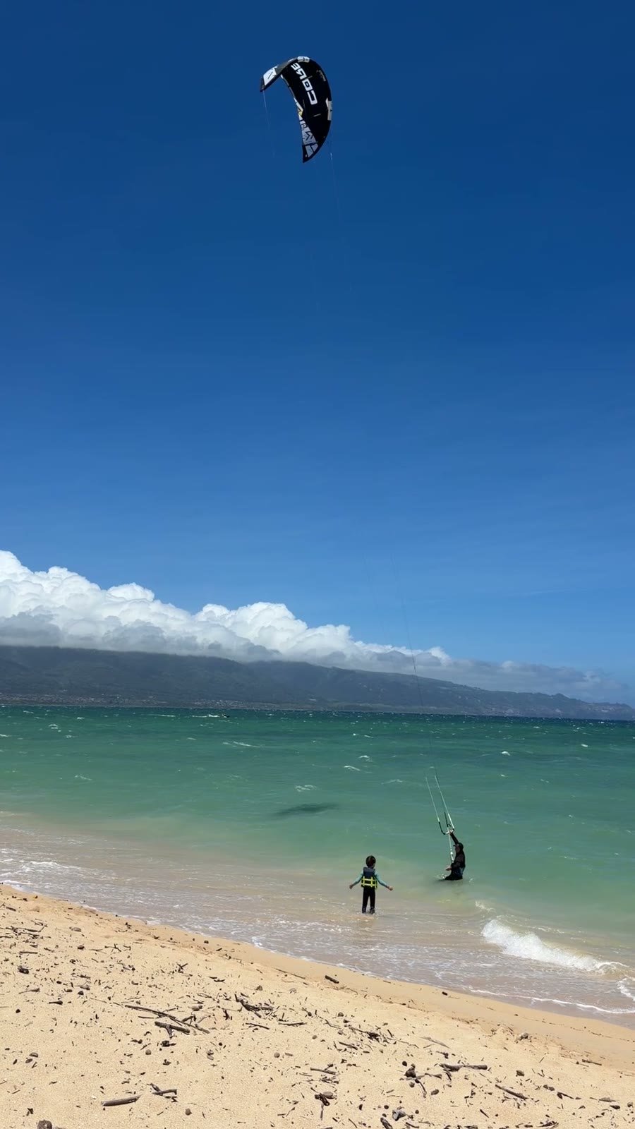 Kite launched at the shoreline, Aiden standing next to Andrey at the water's edge