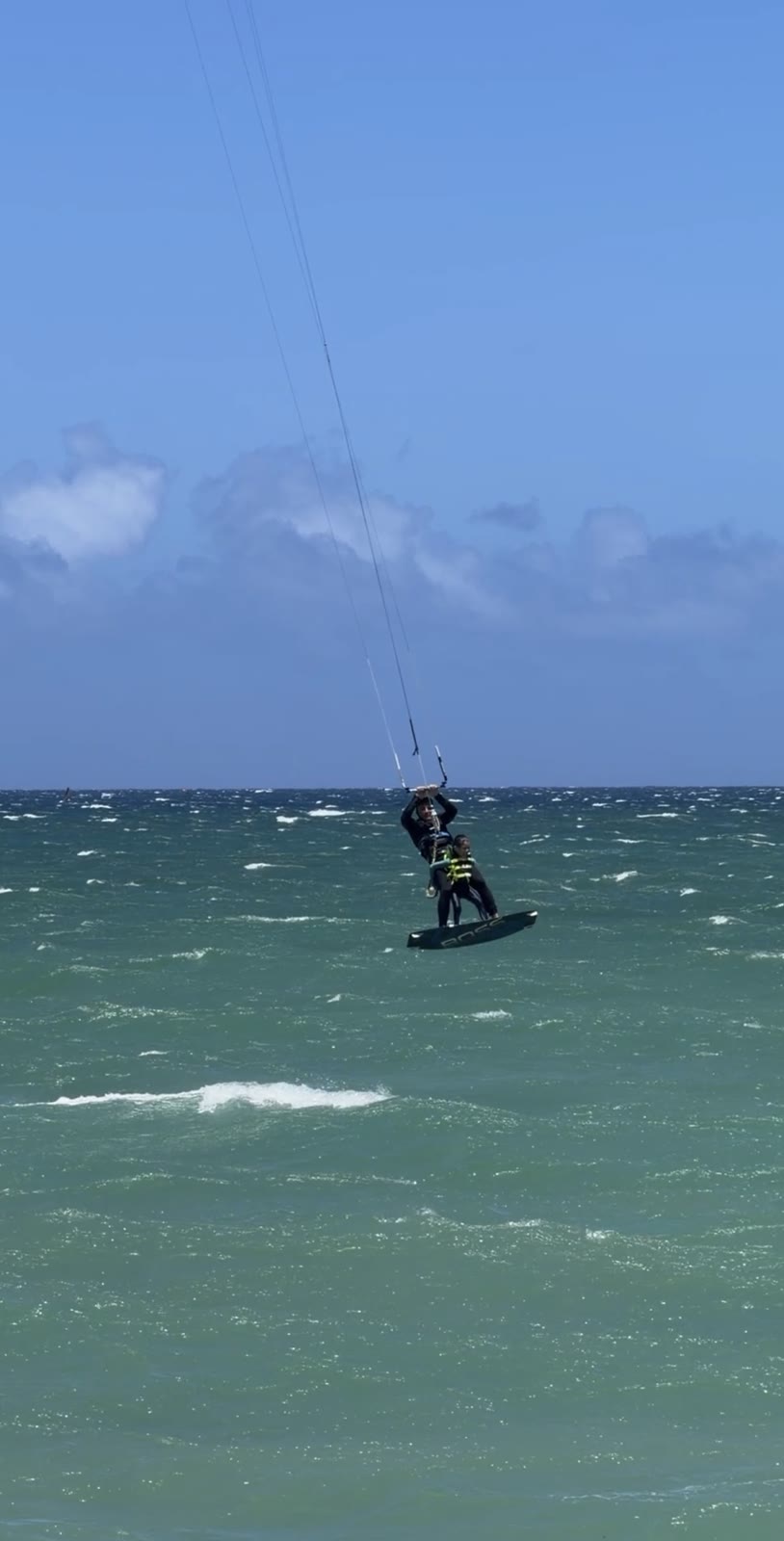 Tandem kite jump, Andrey and Aiden well above the water with the kite lines vertical